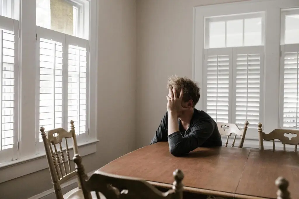 man alone at table struggling with gambling addiction and depression