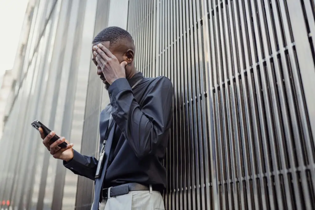 man stressed looking at phone gambling addiction